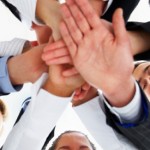 A group of business people gathering together for a team building cheer with their hands together in the middle