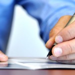 Man writing with a pen on a desk
