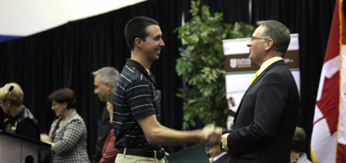 DC student accepting a scholarship from President Don Lovisa.